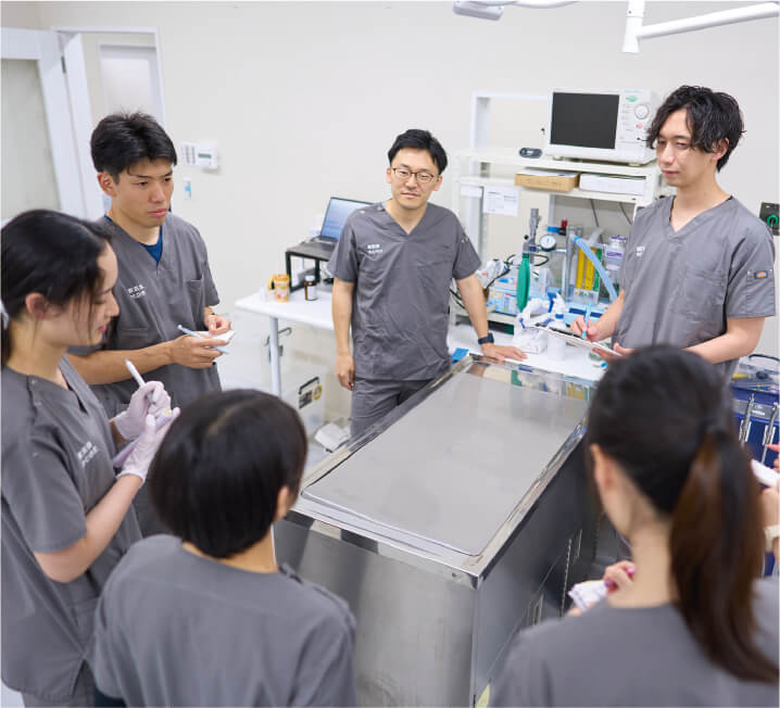 複数の獣医師やスタッフが器具の前に集まり、打ち合わせや研修を行っている様子